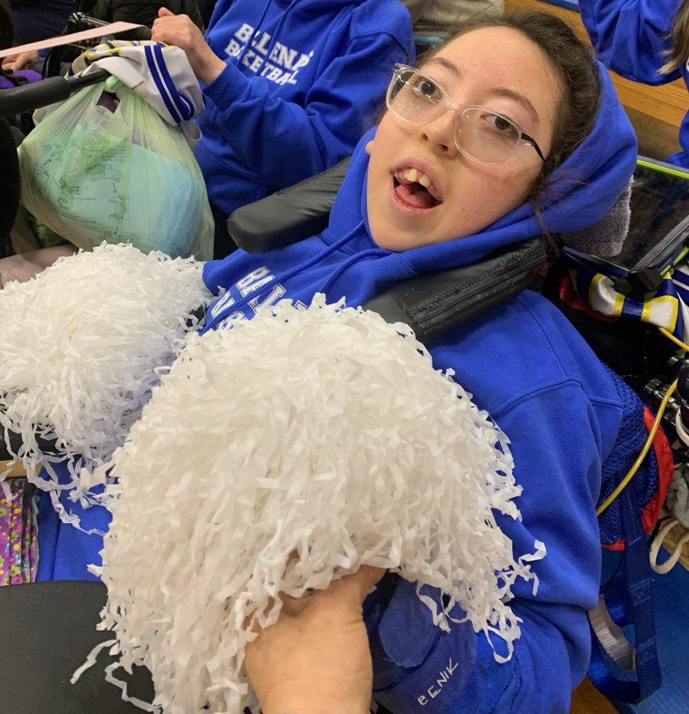 Girl holding white pompoms cheering at a game