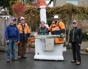 Five smiling people stand in a row, the two in the middle standing in a large white bucket.